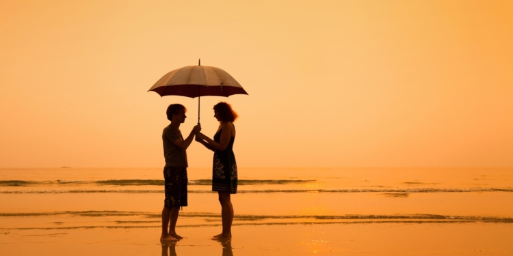 Couple standing on a beach with an umbrella